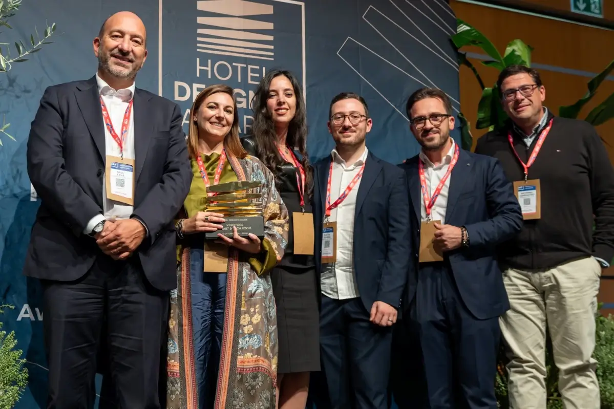 Premiazione IngegnoLab agli Hotel Designer Awards: sei persone sul palco, una donna regge il trofeo Smart & Tech Room
