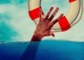 Una mano emerge dall’acqua e cerca di afferrare un salvagente, immagine simbolica della crisi d’impresa