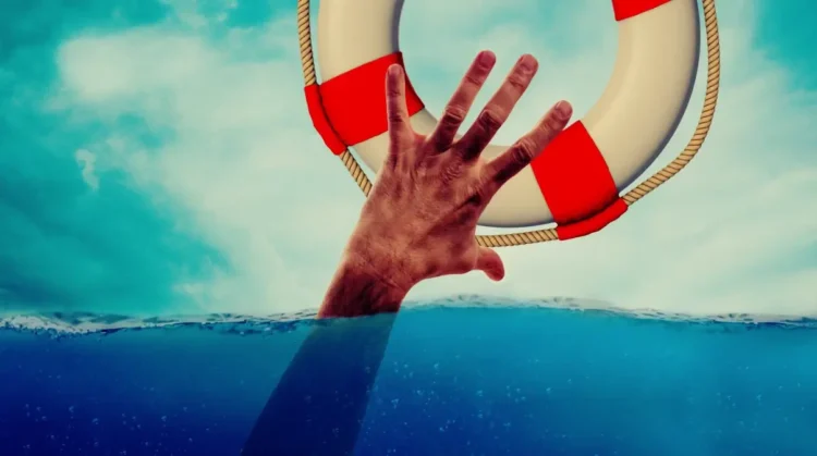 Una mano emerge dall’acqua e cerca di afferrare un salvagente, immagine simbolica della crisi d’impresa