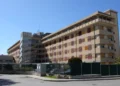 Facciata dell’ospedale Maggiore di Modica, edificio a più piani con persiane rosse e gialle, sotto un cielo sereno