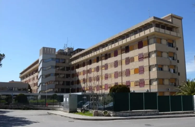 Facciata dell’ospedale Maggiore di Modica, edificio a più piani con persiane rosse e gialle, sotto un cielo sereno