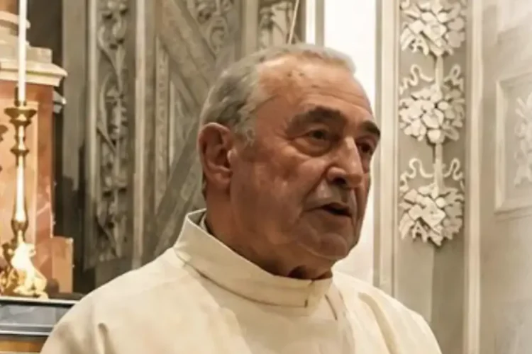 Padre Salvatore Dinatale con l’abito talare chiaro accanto a un altare decorato con stucchi bianchi e candelieri dorati