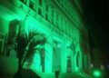 Facciata del Palazzo della Provincia di Ragusa illuminata di verde per la fibrosi cistica, con una palma davanti all’ingresso