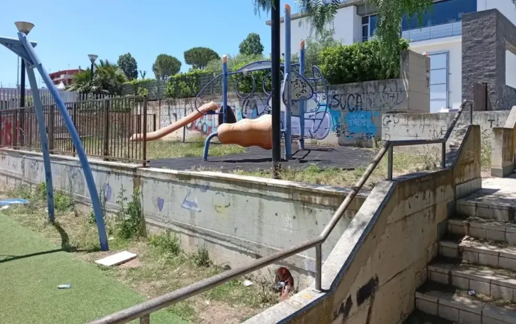 Parco giochi in via Mongibello a Ragusa: scivolo e pavimento antitrauma tra erba alta, rifiuti e muri coperti di graffiti