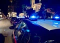Auto dei carabinieri con lampeggianti blu accesi di notte in una strada del centro di Vittoria, con una chiesa illuminata sullo sfondo