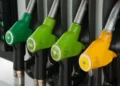 Pistole erogatrici di benzina e gasolio a un distributore, con l’ugello giallo del gasolio in primo piano a destra