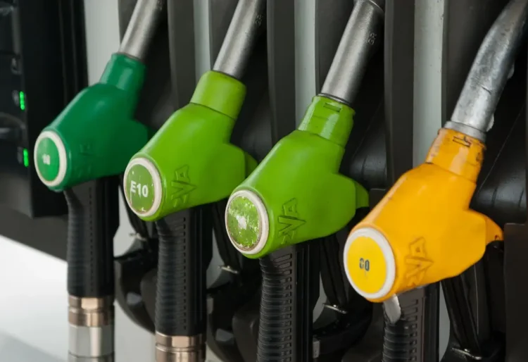 Pistole erogatrici di benzina e gasolio a un distributore, con l’ugello giallo del gasolio in primo piano a destra