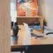Scrivania in legno con computer portatile, tazza, smartphone e cactus in vaso in un ufficio con sedia blu e scaffale