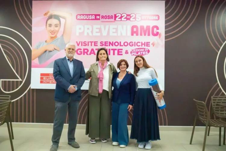 Un uomo e tre donne davanti allo striscione rosa delle visite senologiche gratuite di Ragusa in Rosa all’Interspar Le Dune