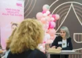 Donna con badge LILT a un tavolo con due donne nello spazio PreveniAMO, nei giorni delle visite senologiche gratuite a Ragusa