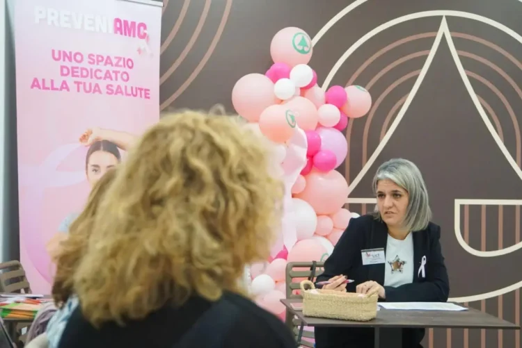 Donna con badge LILT a un tavolo con due donne nello spazio PreveniAMO, nei giorni delle visite senologiche gratuite a Ragusa