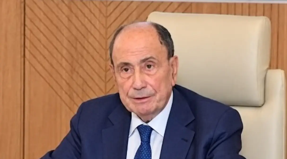 Renato Schifani, che ha commentato le variazioni di bilancio approvate all’Ars, in abito blu seduto davanti a una parete in legno