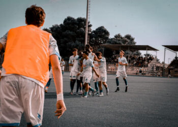 Giocatori del Santa Croce Soccer in maglia bianca esultano dopo un gol; in primo piano un compagno con casacca arancione