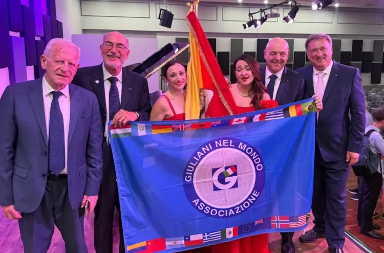 Silvia Di Falco e Cristina Gianino in abito rosso a Johannesburg, con quattro uomini, la bandiera siciliana e quella dei Giuliani nel Mondo