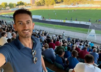 Simone Digrandi in un selfie in tribuna durante una partita di calcio, con il pubblico sugli spalti alle sue spalle