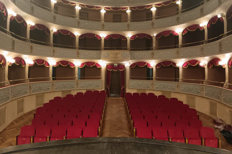 Platea del Teatro Garibaldi di Modica con poltrone rosse, palchi su tre ordini e tendaggi bordeaux