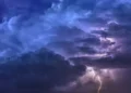 Nuvole temporalesche viola e blu solcate da fulmini nel cielo notturno, foto di repertorio per l’allerta gialla