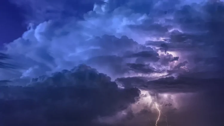 Nuvole temporalesche viola e blu solcate da fulmini nel cielo notturno, foto di repertorio per l’allerta gialla