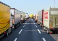 Mezzi dell’autotrasporto incolonnati su due file lungo un’autostrada a più corsie, con la carreggiata centrale sgombra