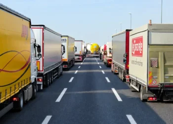 Mezzi dell’autotrasporto incolonnati su due file lungo un’autostrada a più corsie, con la carreggiata centrale sgombra