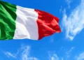Bandiera tricolore italiana che sventola contro un cielo azzurro con nuvole sottili, simbolo del 4 novembre