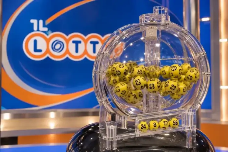 Urna trasparente con palline gialle numerate davanti a un logo del Lotto, in uno studio televisivo di estrazione