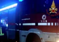 Mezzo dei vigili del fuoco con lampeggianti blu accesi di notte e un pompiere di spalle, intervento dopo un incidente a Ragusa
