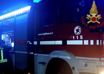 Mezzo dei vigili del fuoco con lampeggianti blu accesi di notte e un pompiere di spalle, intervento dopo un incidente a Ragusa