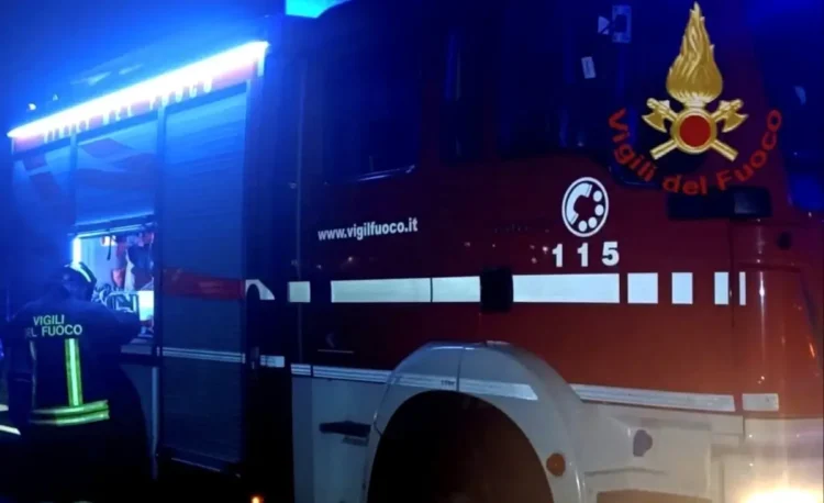 Mezzo dei vigili del fuoco con lampeggianti blu accesi di notte e un pompiere di spalle, intervento dopo un incidente a Ragusa
