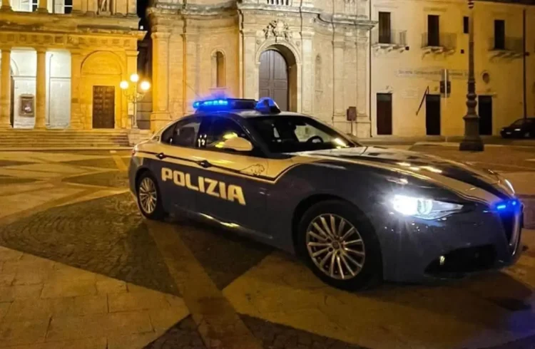 Volante della Polizia di Stato con lampeggianti blu in una piazza di notte, arresto per furto in abitazione a Vittoria