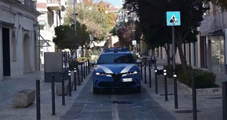Auto della Polizia di Stato in una via pedonale lastricata di Ragusa, tra dissuasori neri, alberi e negozi