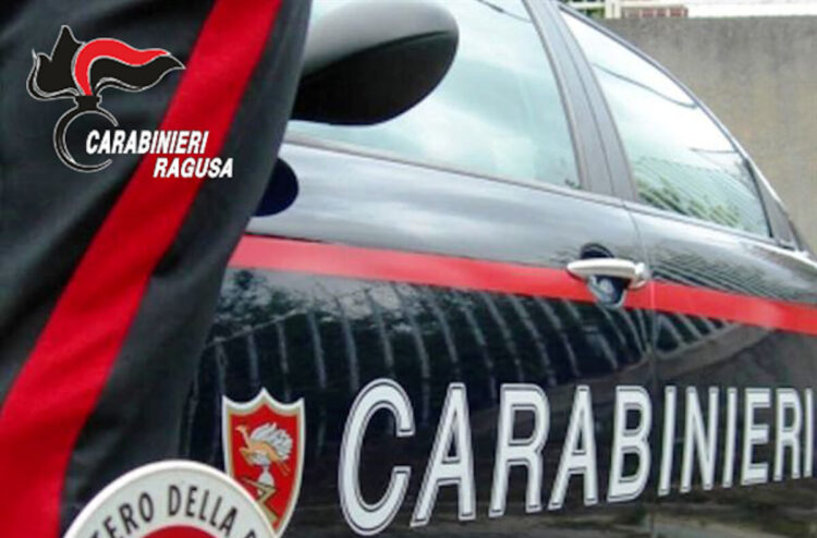 Fiancata di un’auto dei carabinieri con la banda rossa e la divisa di un militare; in alto il logo Carabinieri Ragusa
