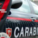 Fiancata di un’auto dei carabinieri con la banda rossa e la divisa di un militare; in alto il logo Carabinieri Ragusa