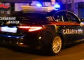 Auto dei Carabinieri vista da dietro, di notte in una strada, con lampeggianti blu accesi e logo Carabinieri Ragusa in sovrimpressione