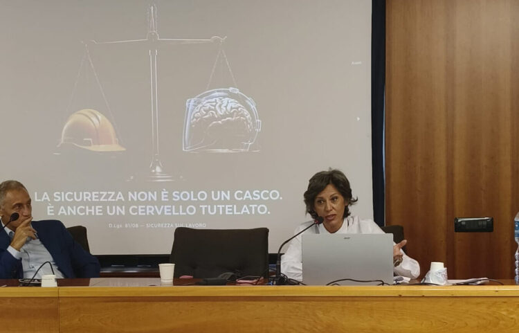 Una relatrice parla al microfono durante la presentazione de L’Aliena in Azienda, con la slide sulla sicurezza psicologica