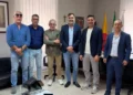 Sei uomini in posa in un ufficio con le bandiere di Sicilia e Italia, dopo l’incontro Iacp-Cna sugli alloggi popolari a Ragusa
