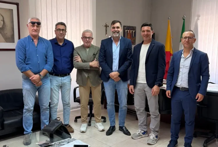 Sei uomini in posa in un ufficio con le bandiere di Sicilia e Italia, dopo l’incontro Iacp-Cna sugli alloggi popolari a Ragusa