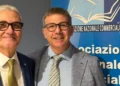 Due uomini in giacca e cravatta sorridono davanti al pannello Anc dell’Associazione nazionale commercialisti