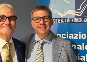 Due uomini in giacca e cravatta sorridono davanti al pannello Anc dell’Associazione nazionale commercialisti