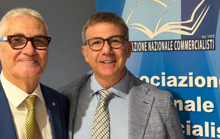 Due uomini in giacca e cravatta sorridono davanti al pannello Anc dell’Associazione nazionale commercialisti