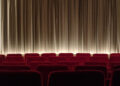 Sala di cinema con poltrone rosse e pubblico prima della proiezione