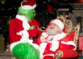 Antonino Aggius Vella vestito da Babbo Natale, seduto su un trono dorato, sorride a una persona travestita da Grinch