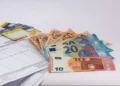 Banconote da 10, 20 e 50 euro aperte a ventaglio accanto a carte di pagamento e a un estratto conto, tema assegno unico