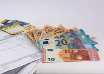 Banconote da 10, 20 e 50 euro aperte a ventaglio accanto a carte di pagamento e a un estratto conto, tema assegno unico