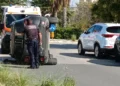 Auto ribaltata su un fianco in una strada di Comiso, un agente della Polizia locale accanto e un'ambulanza del 118 dietro