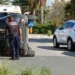 Auto ribaltata su un fianco in una strada di Comiso, un agente della Polizia locale accanto e un'ambulanza del 118 dietro