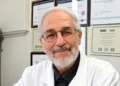 Antonio Caruso, biologo di Modica autore della ricerca Bibbia e Dna, in camice bianco davanti a una parete di attestati