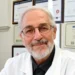 Antonio Caruso, biologo di Modica autore della ricerca Bibbia e Dna, in camice bianco davanti a una parete di attestati