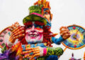 Carro allegorico di carnevale con un grande personaggio in cartapesta dal cilindro verde, capelli rossi e due orologi colorati