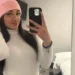 Carola Battaglia, giovane di Vittoria, in un selfie allo specchio con berretto rosa e maglione bianco a collo alto